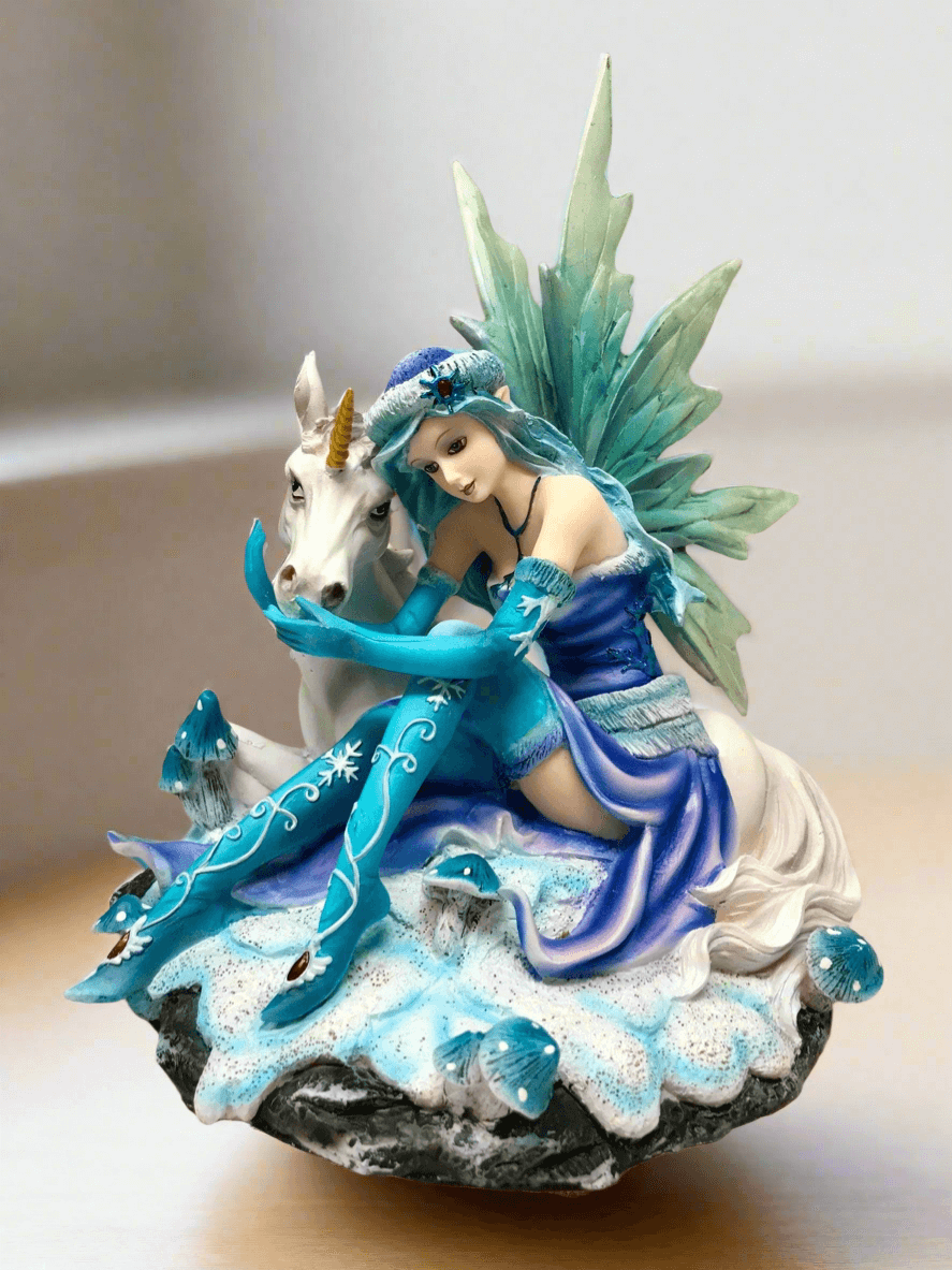 Statuette décorative représentant une fée d'hiver bleue assise avec une licorne